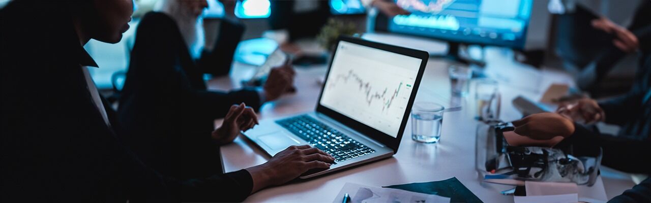 man-looking-at-metrics-on-a-laptop-with-people-around